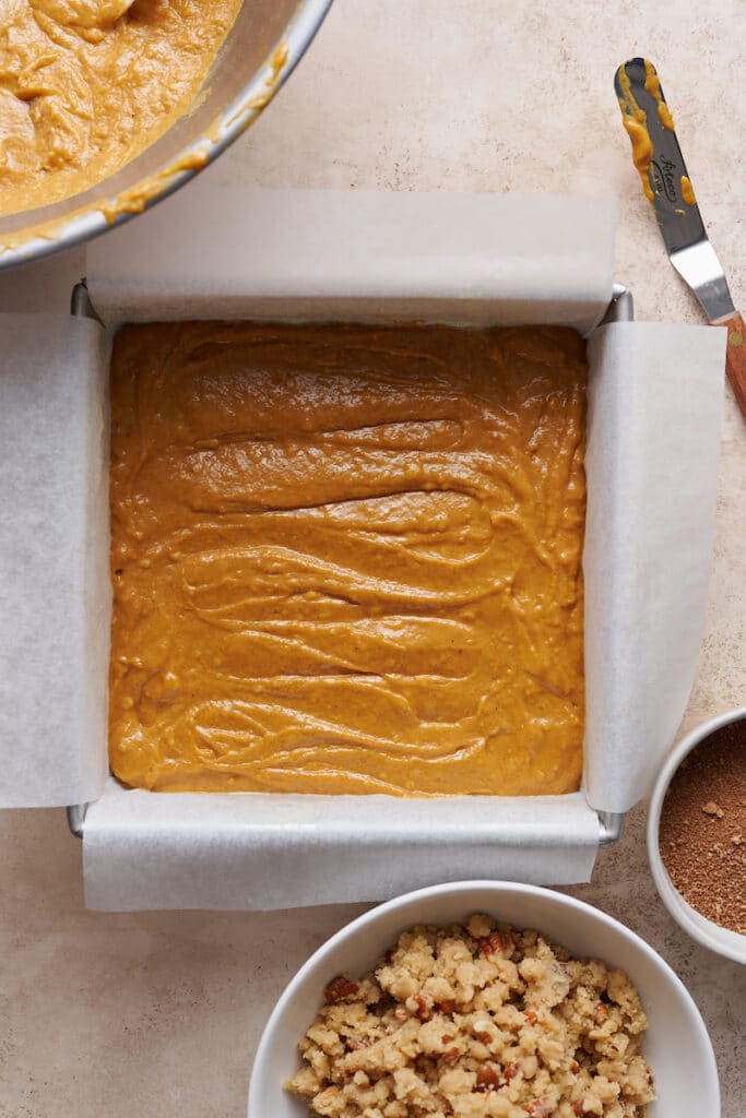 Pumpkin coffee cake in baking pan with crumb topping on the side.