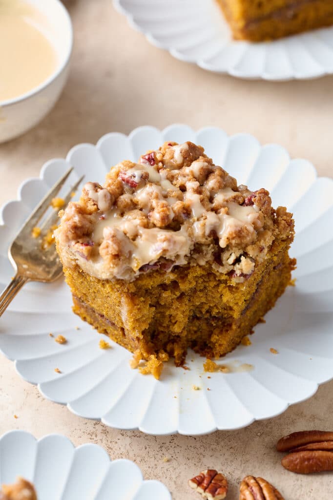 Slice of pumpkin coffee cake on a dessert plate with a fork and coffee on the side.