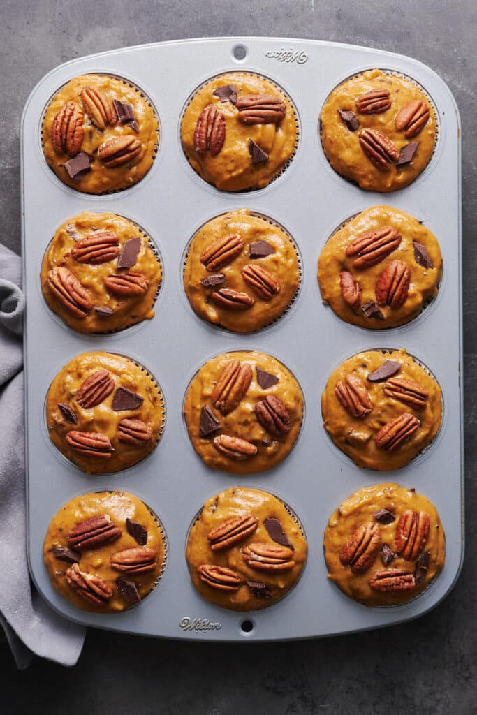 Muffin pan filled with pumpkin muffin batter.