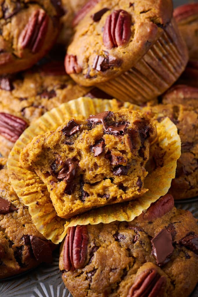 Pumpkin chocolate chip muffin in paper liner with a bite taken out. 