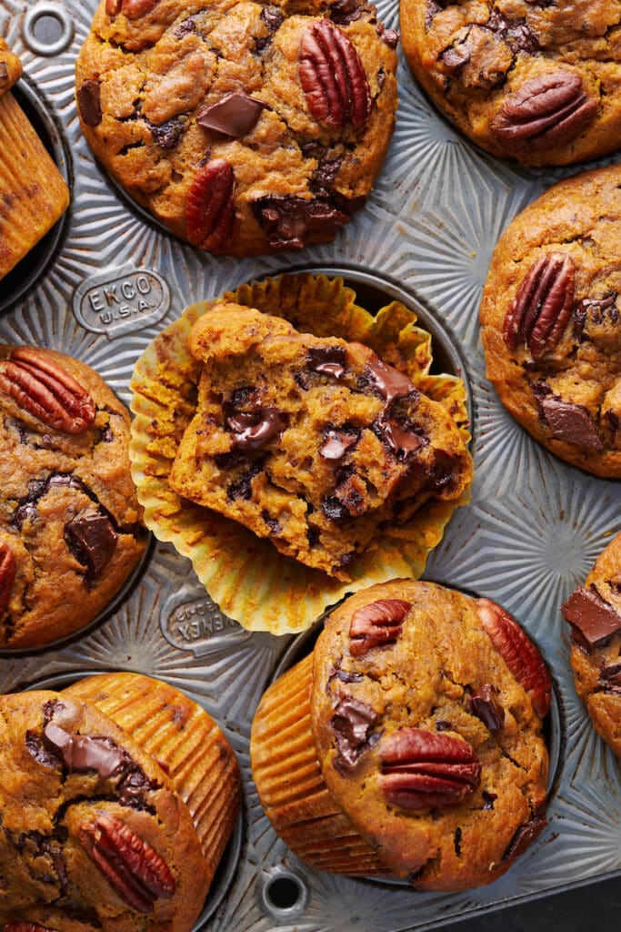 Pumpkin chocolate chip muffin in paper liner with a bite taken out.