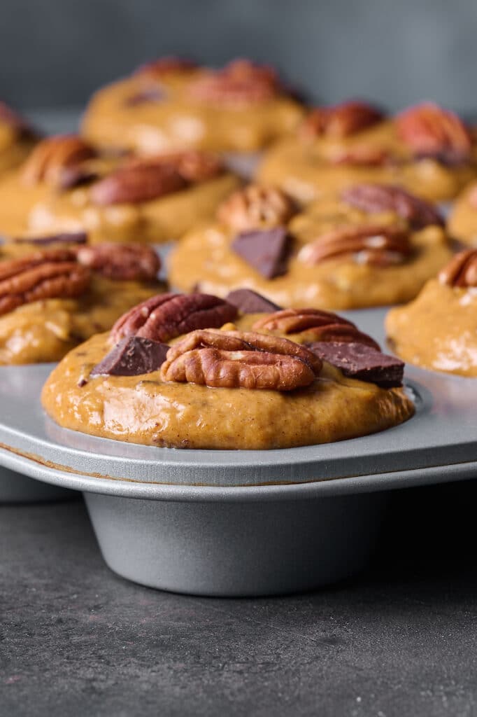 A muffin tin full with pumpkin chocolate chip muffin batter. 