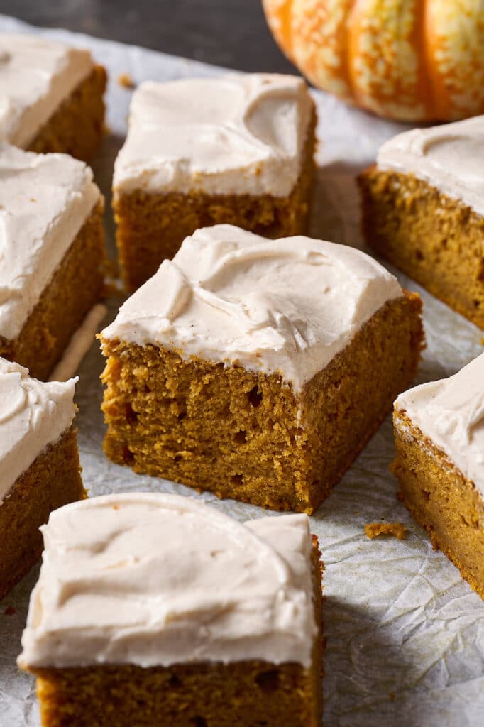 Pumpkin Cake sliced into squares on a piece of parchment paper. 