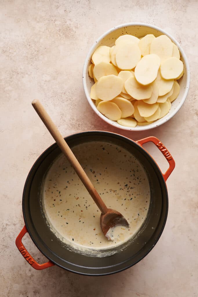 Cream sauce and thinly sliced potatoes for scalloped potatoes gratin.