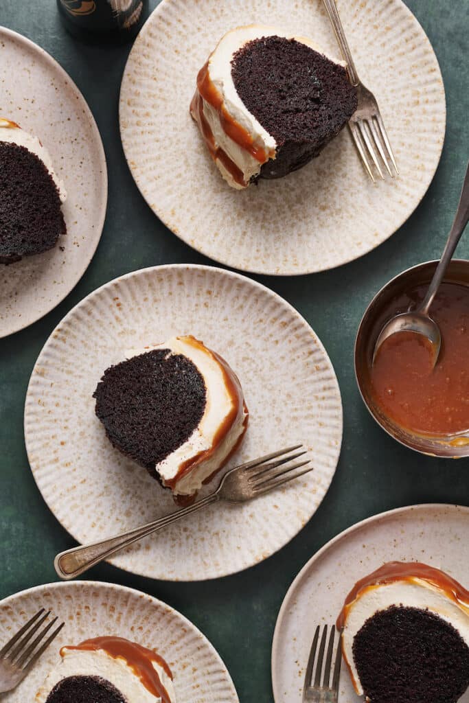 Slices of Guinness chocolate cake on dessert plates with caramel on the side.