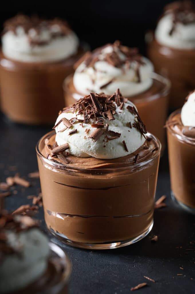 Small dish of chocolate mousse topped with whipped cream and chocolate shavings.