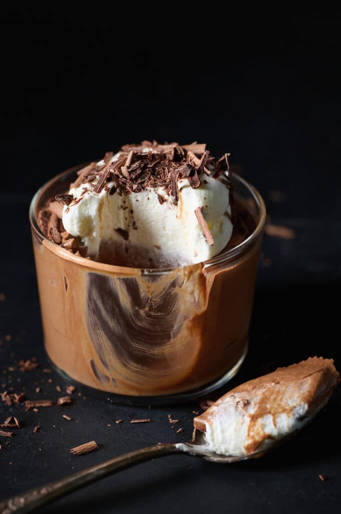 Small dish of chocolate mousse topped with whipped cream and chocolate shavings.