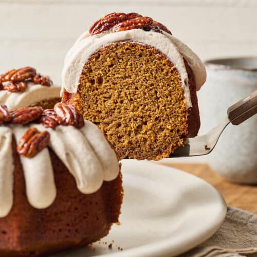 Slice of pumpkin bundt cake being lifted up from plate with cake server.