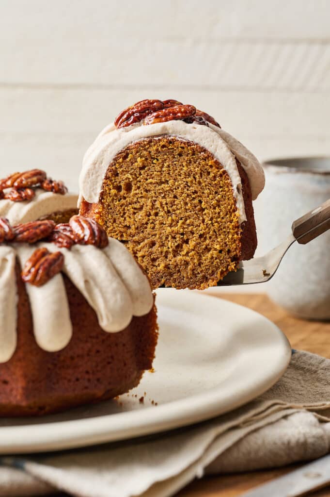 Slice of pumpkin bundt cake being lifted up from plate with cake server. 