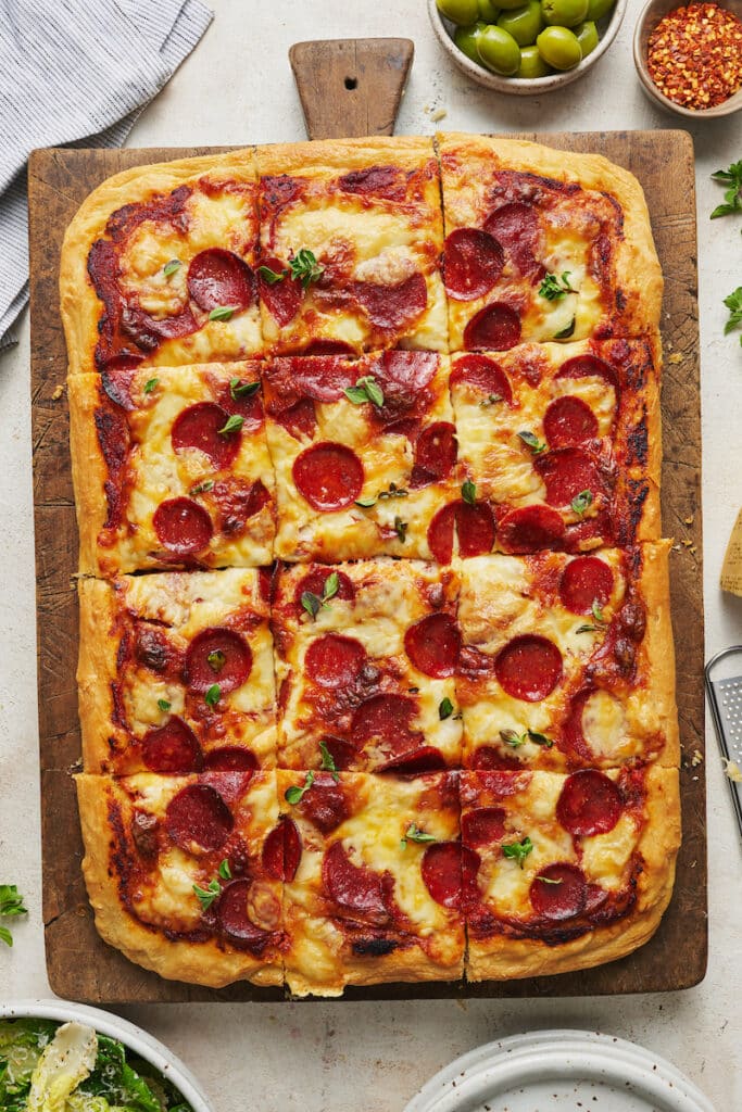 Pepperoni pizza on a wooden cutting board. 