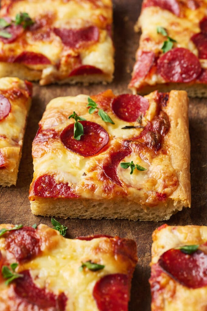 Slice of pepperoni pizza on wooden cutting board.