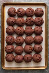 Chocolate crinkle cookie dough balls on baking sheet.