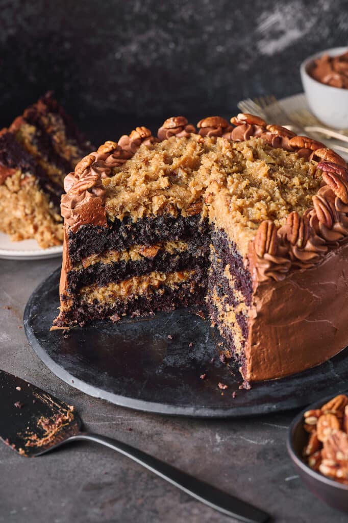 German Chocolate cake cut into with a slice missing and cake server on platter. 