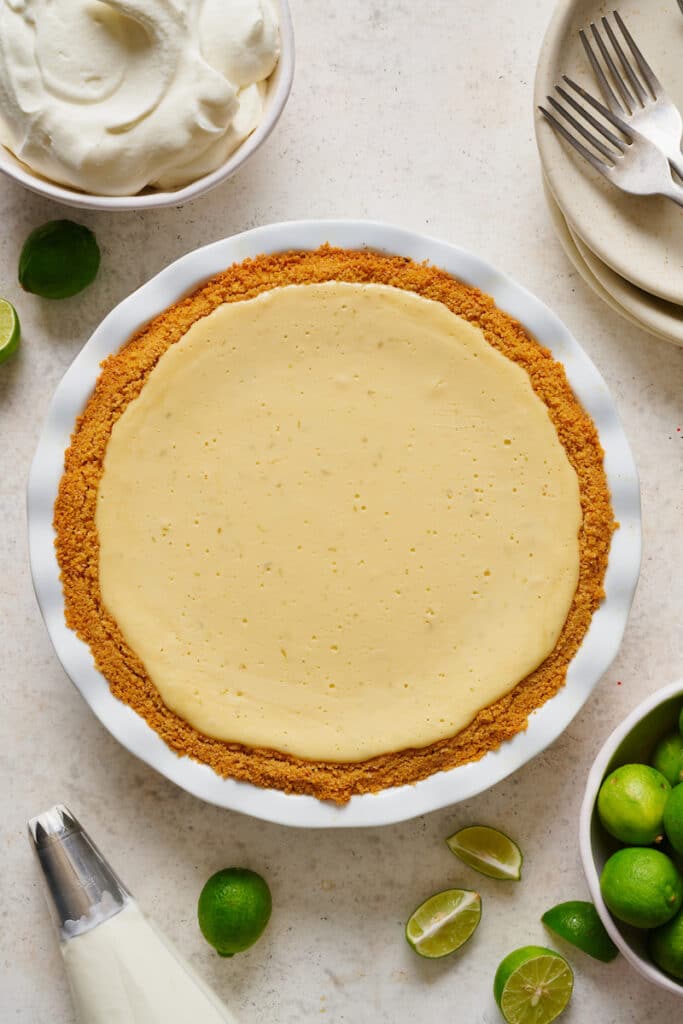 Key lime pie in pie plate ready to be topped with whipped cream and lime zest. 