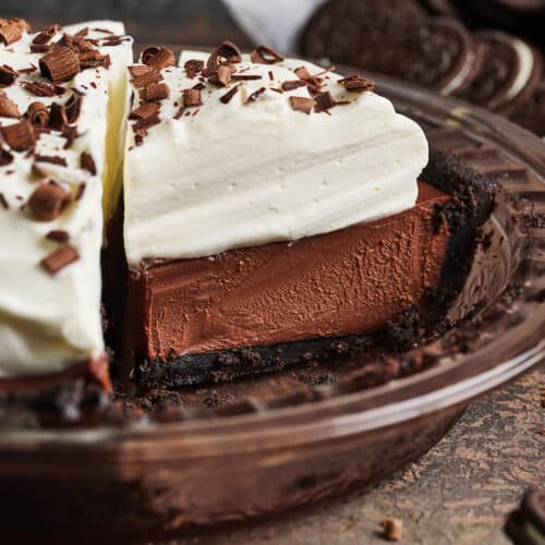 Slice of chocolate cream pie in the baking dish with whipped cream on top.