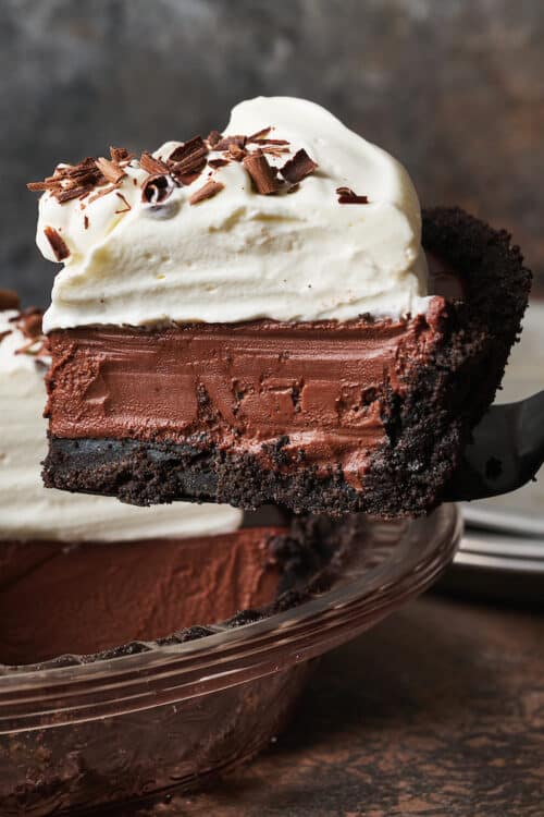 Egg free dessert featuring a chocolate cream pie being lifted out of the pie plate.