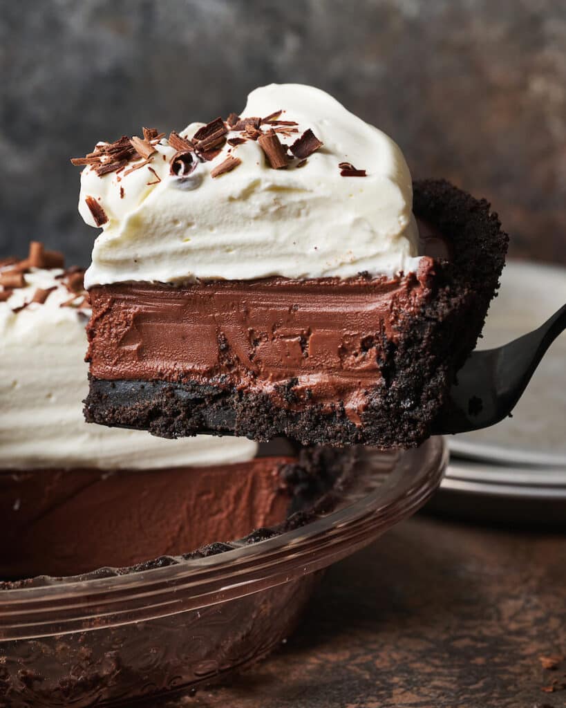 Egg free dessert featuring a chocolate cream pie being lifted out of the pie plate.