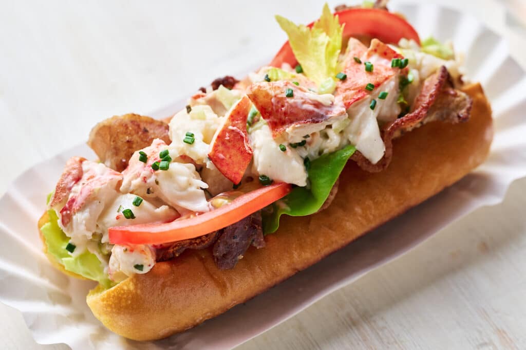 Learn how to make lobster rolls with this easy lobster roll recipe! The lobster salad contains cooked lobster meat, lemon juice, melted butter, mayo, and fresh herbs. The lobster mixture is piled high on toasted split top buns and topped with bacon, lettuce, and tomato! We love to serve these with crunchy potato chips and ice cold beer.
