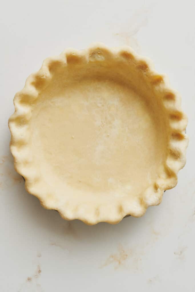 Pie crust rolled out with a crimped pie shell for the pumpkin pie.