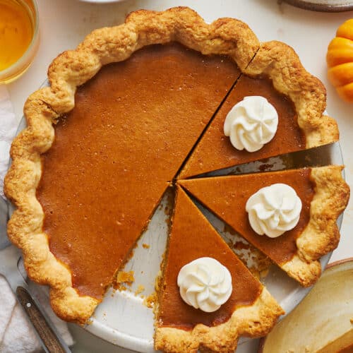 A bourbon pumpkin pie in the pie plate with whipped cream on top.