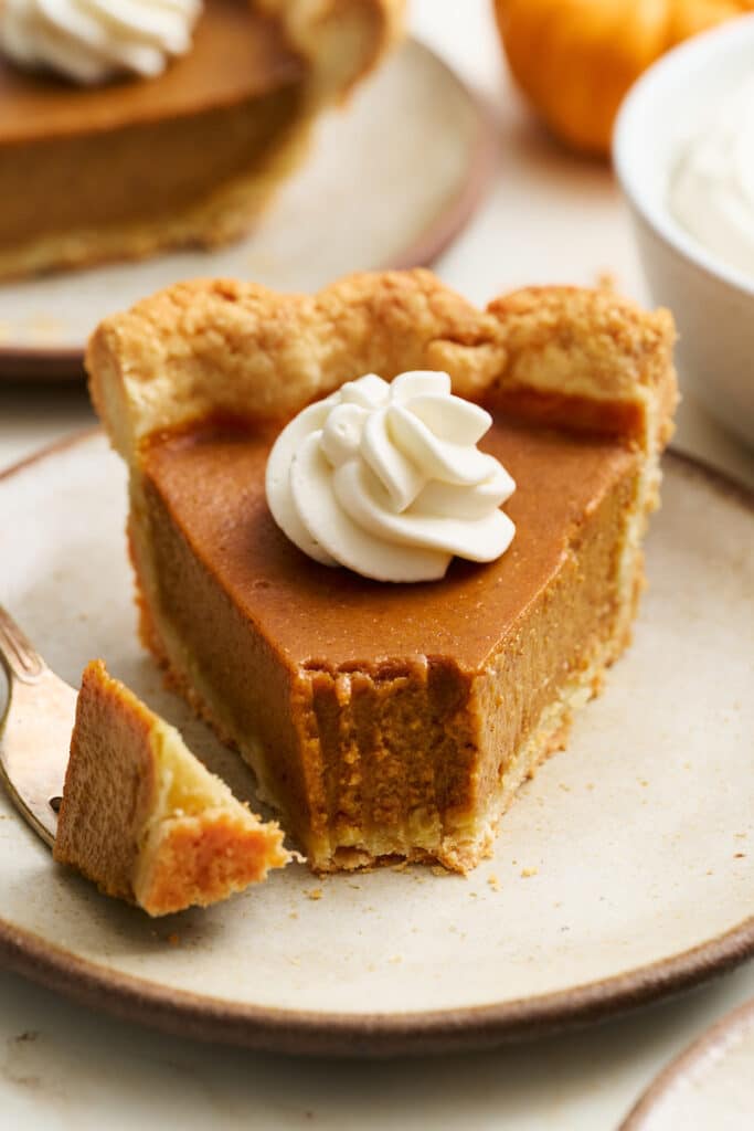 Slice of bourbon pumpkin pie with a bite taken out of it.