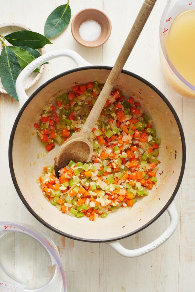 Large dutch oven with carrots, onion, and celery for homemade chicken noodle soup.