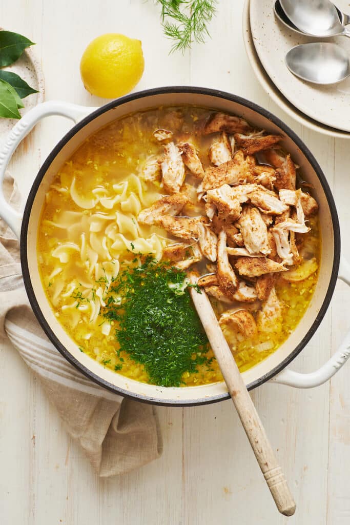 Stirring fresh dill, cooked chicken, and lemon juice into chicken noodle soup.