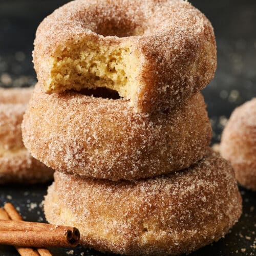 Stack of cinnamon sugar donuts with cinnamon sticks on the side.
