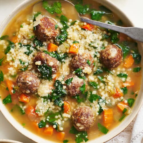 Bowl of Italian wedding soup with cheese on top.