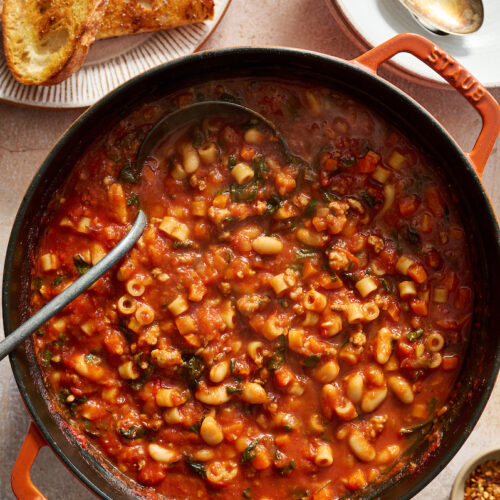 Dutch oven full of pasta fagioli soup with ladle.