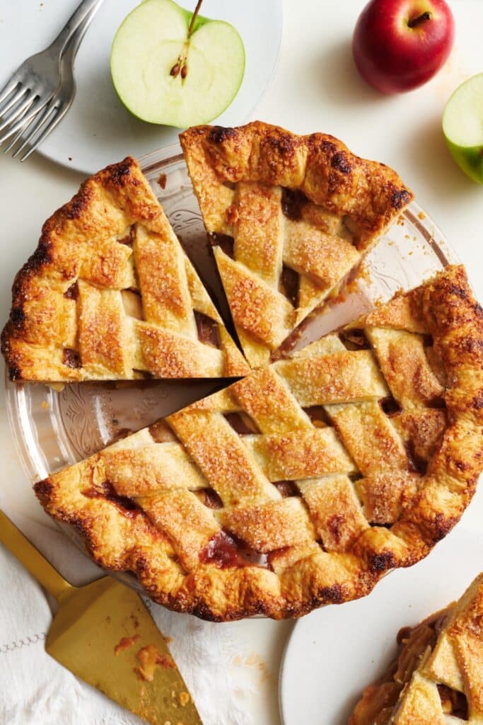 A slice of homemade apple pie with apple pie filling and a flaky pie crust plus vanilla ice cream.