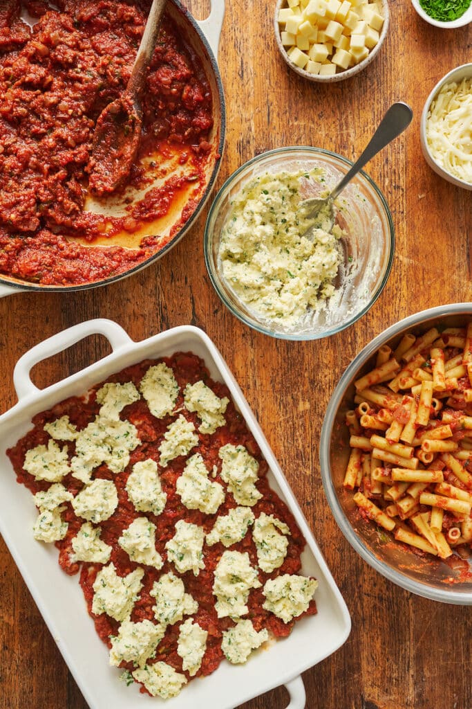 Ingredients for baked ziti on a brown table. 