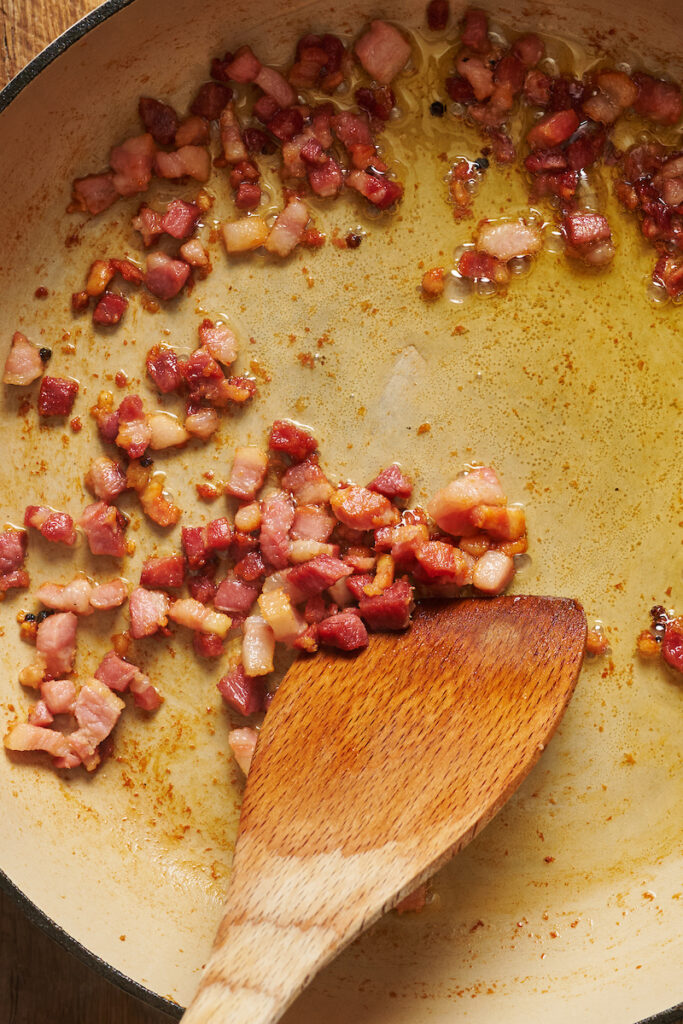 Pancetta cooking in a large pan for bolognese sauce.