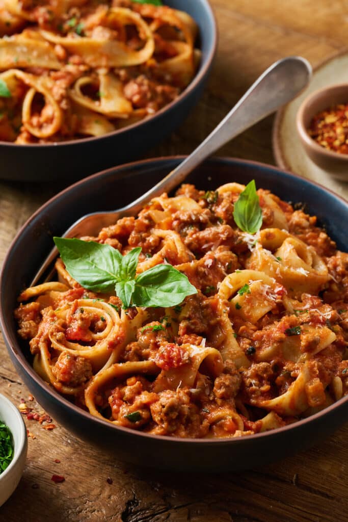 A bowl of pasta topped with my bolognese sauce and fresh basil.