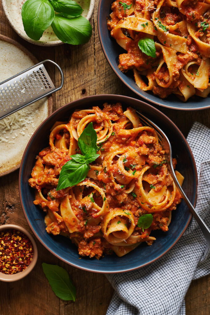 A bowl of pasta topped with my bolognese sauce and fresh basil.