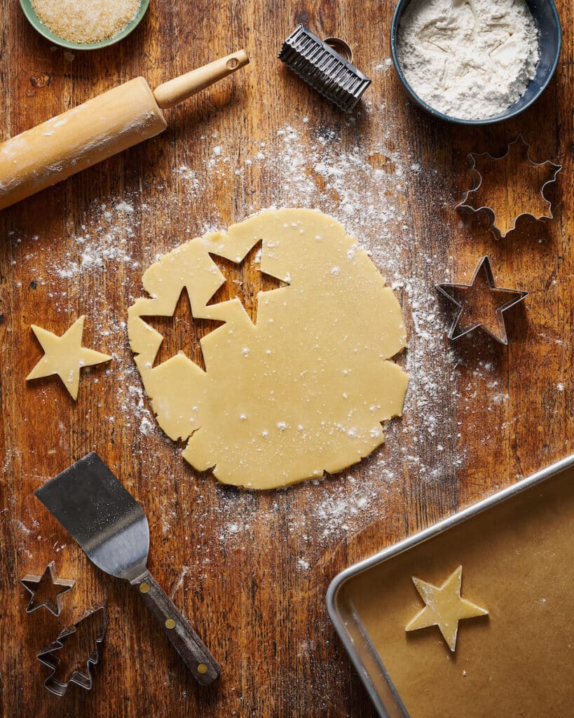 Cookie dough and cookie cutters for Christmas cookies on wooden table.