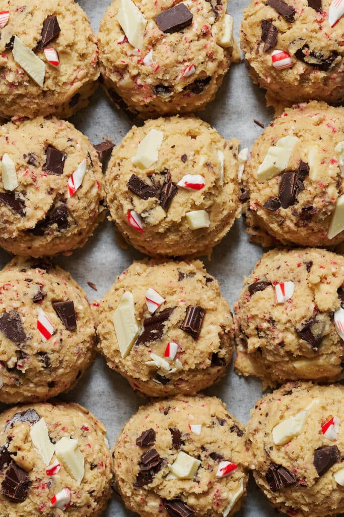 Candy cane cookie dough scooped onto baking sheet.