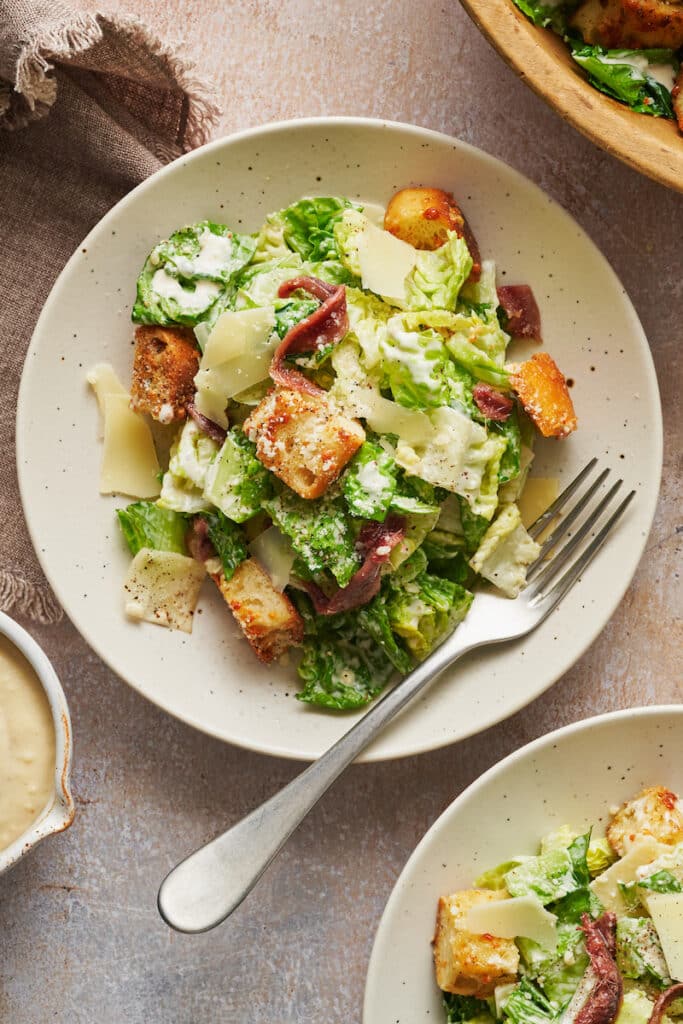 A big bowl of homemade Caesar salad topped with anchovies and croutons.