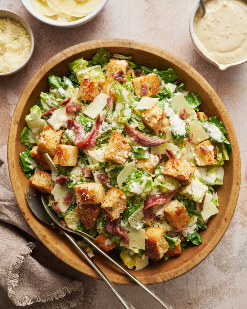 A big bowl of homemade Caesar salad topped with anchovies and croutons.