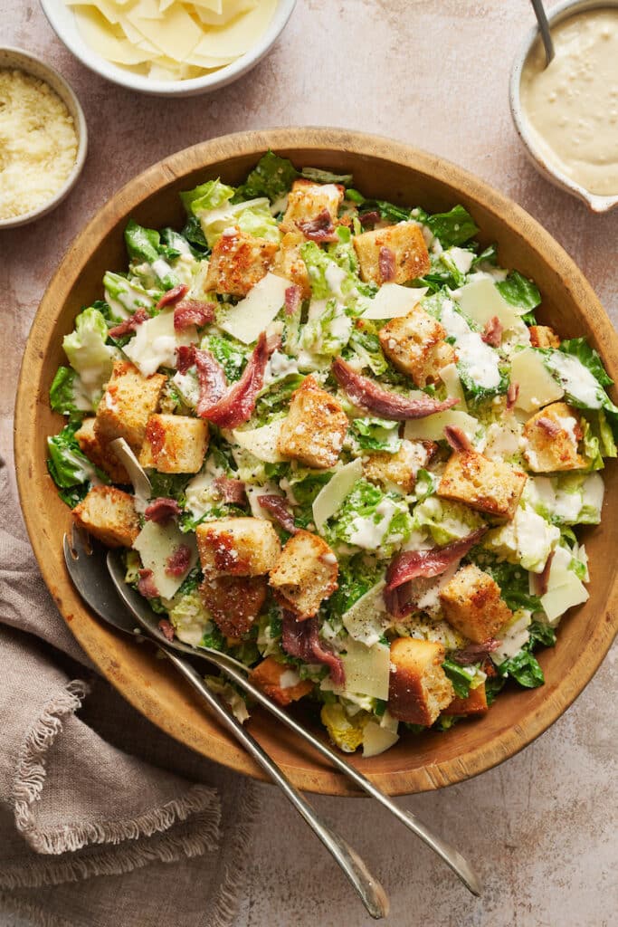 A big bowl of homemade Caesar salad topped with anchovies and croutons.