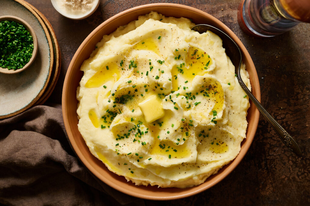 Bowl of mashed potatoes topped with melted butter.