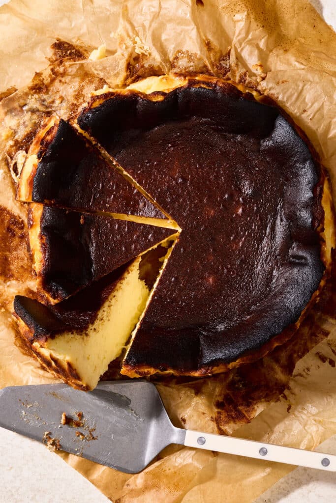 Basque cheesecake sliced on parchment paper.