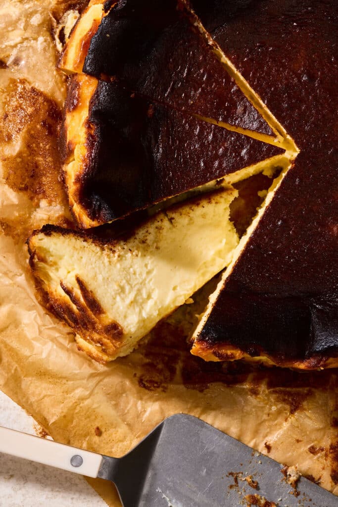 Slice of basque cheesecake on brown parchment paper.