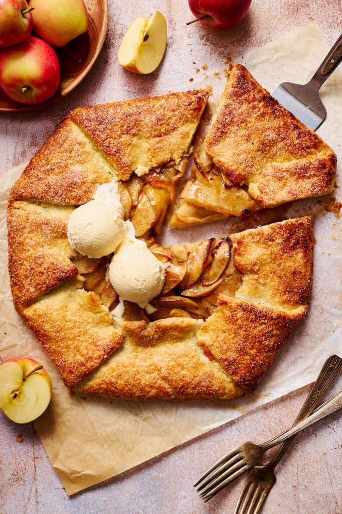 Apple galette with vanilla ice cream on top of parchment paper.