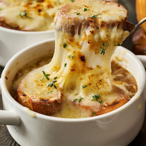 French onion soup with melted cheese being spooned off the top.
