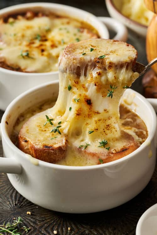 French onion soup with melted cheese being spooned off the top.