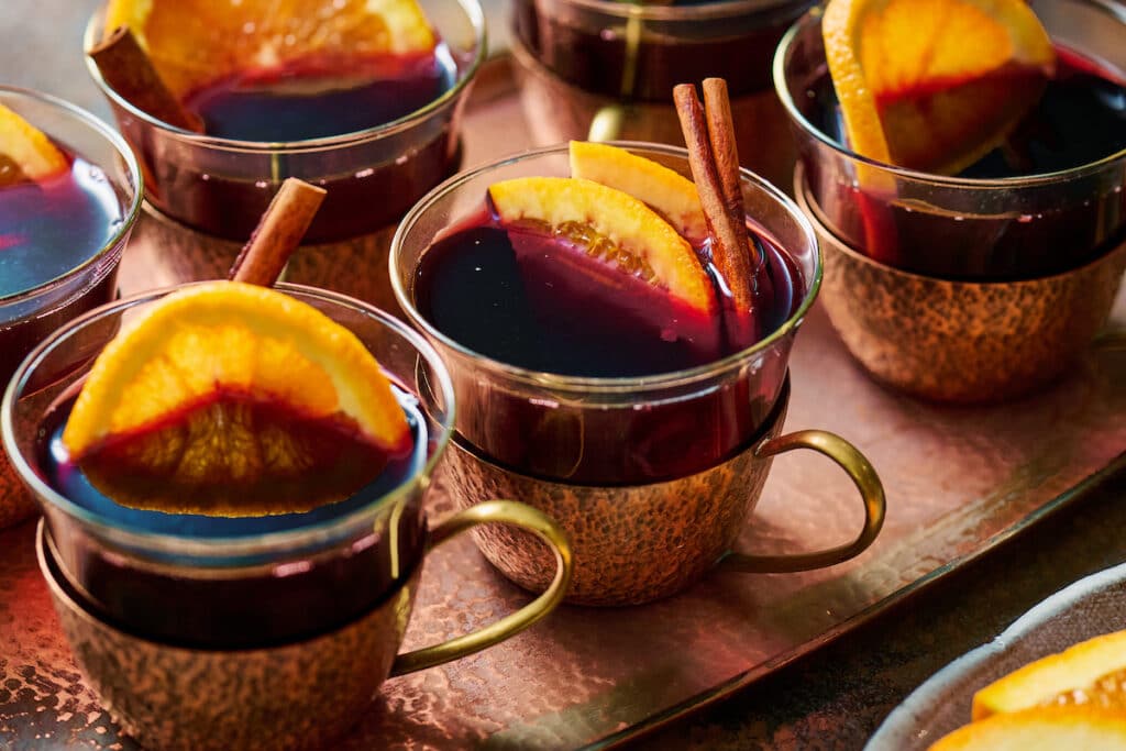 Mulled wine in glasses with orange slices and cinnamon sticks.